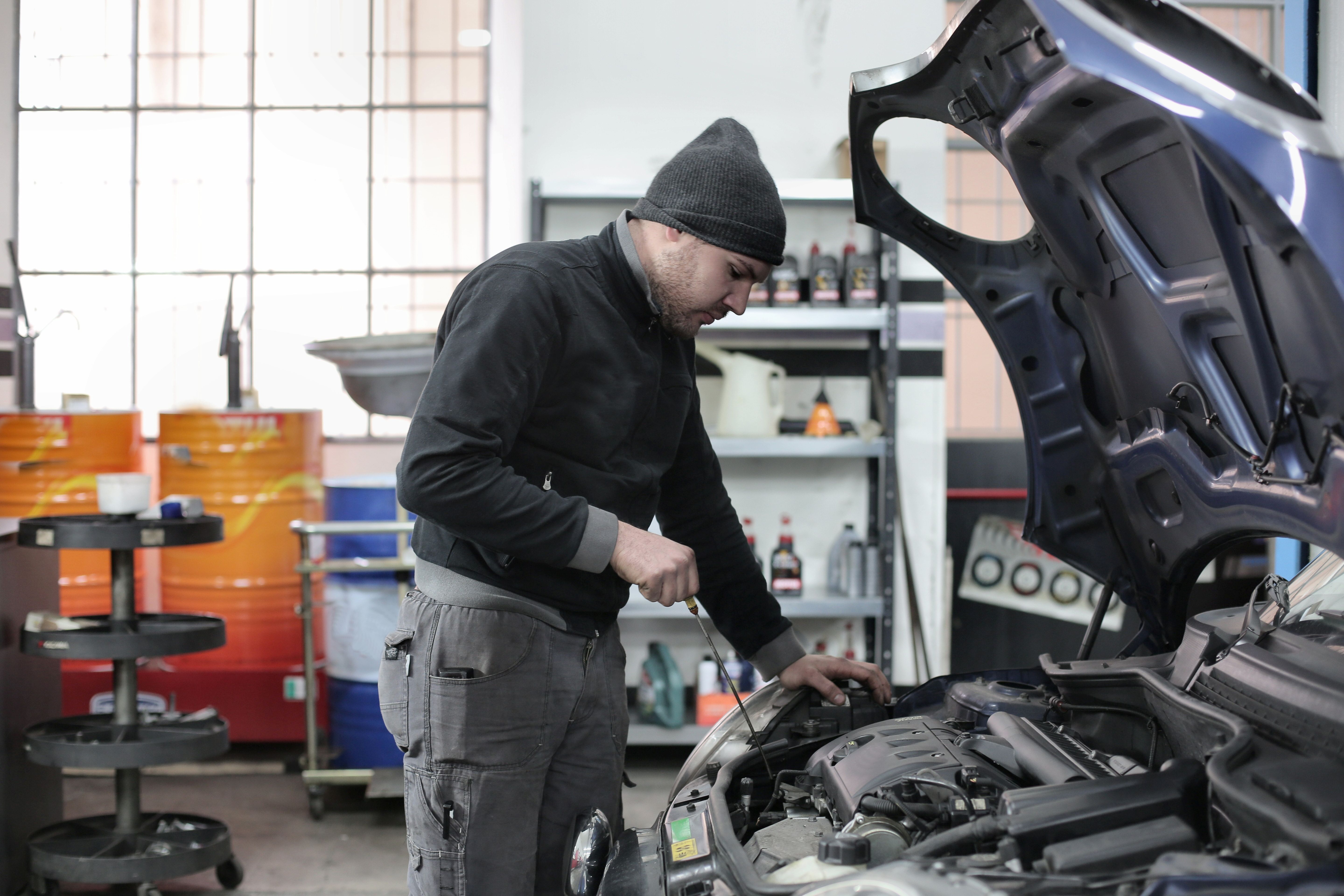 Mecánico revisando el motor de un auto con la capota levantada en un taller mecánico de Buenos Aires