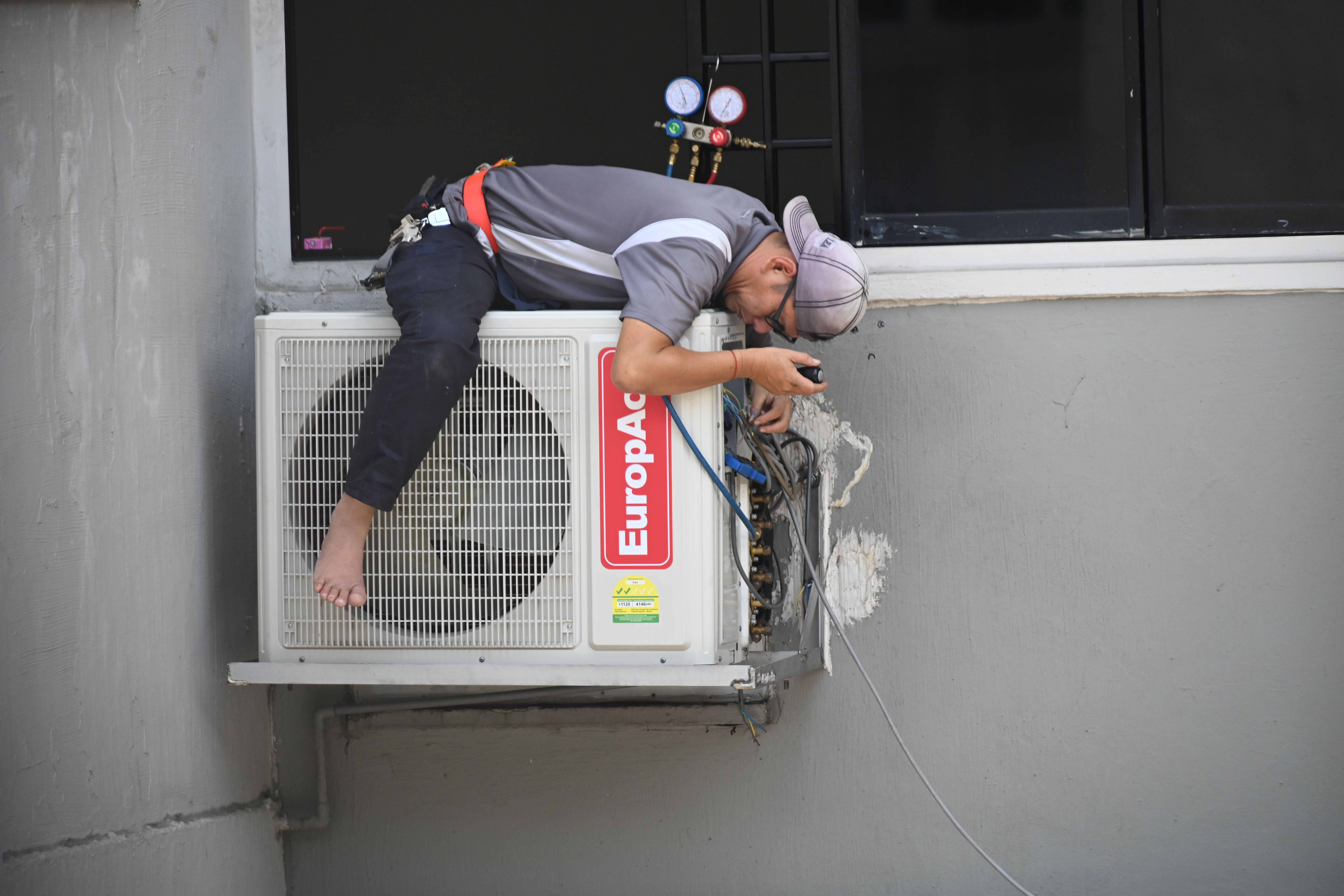 Técnico de climatización instalando un split de aire acondicionado en la pared de un departamento de Buenos Aires