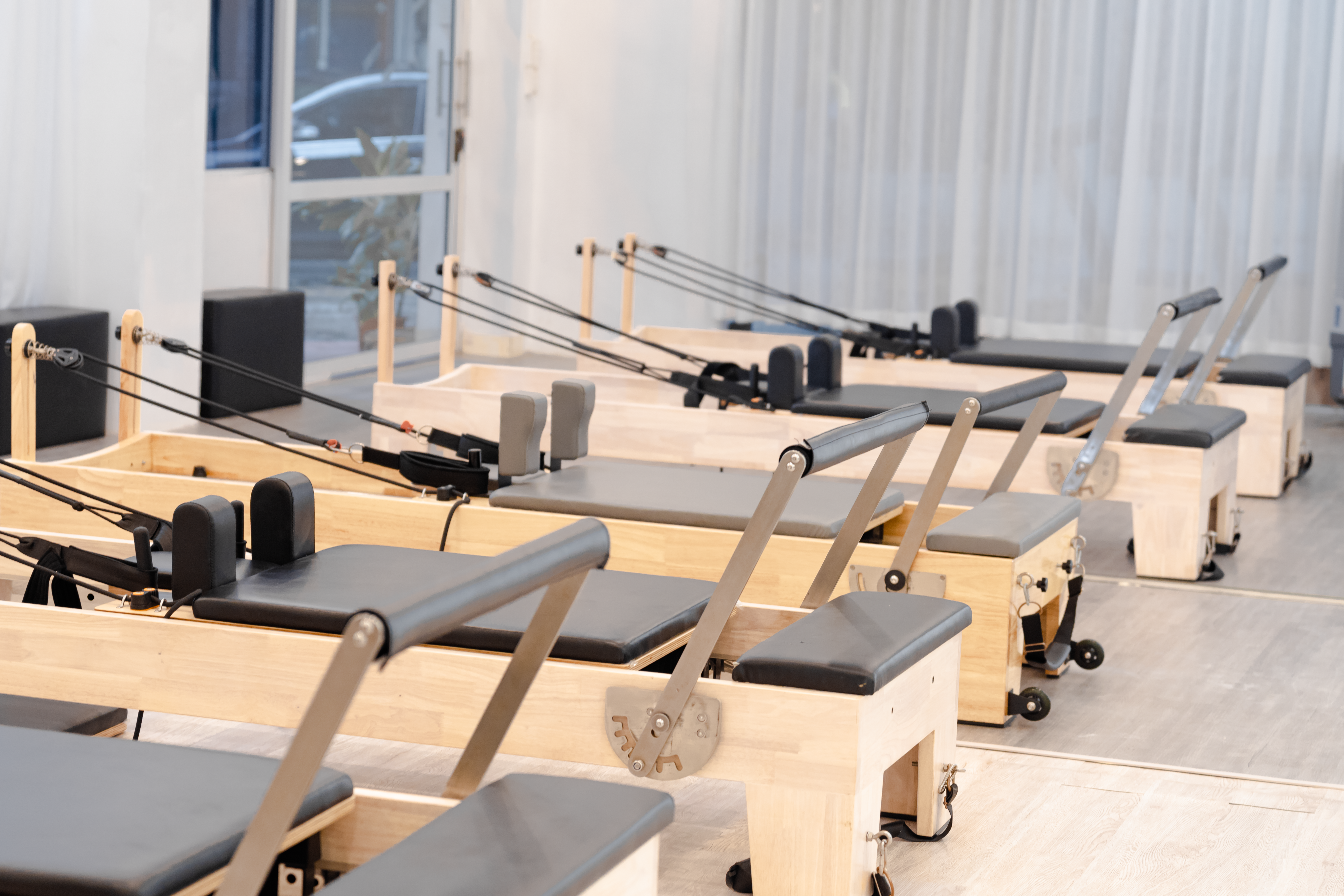 Clase reducida de pilates reformer con instructora corrigiendo la postura en un estudio porteño