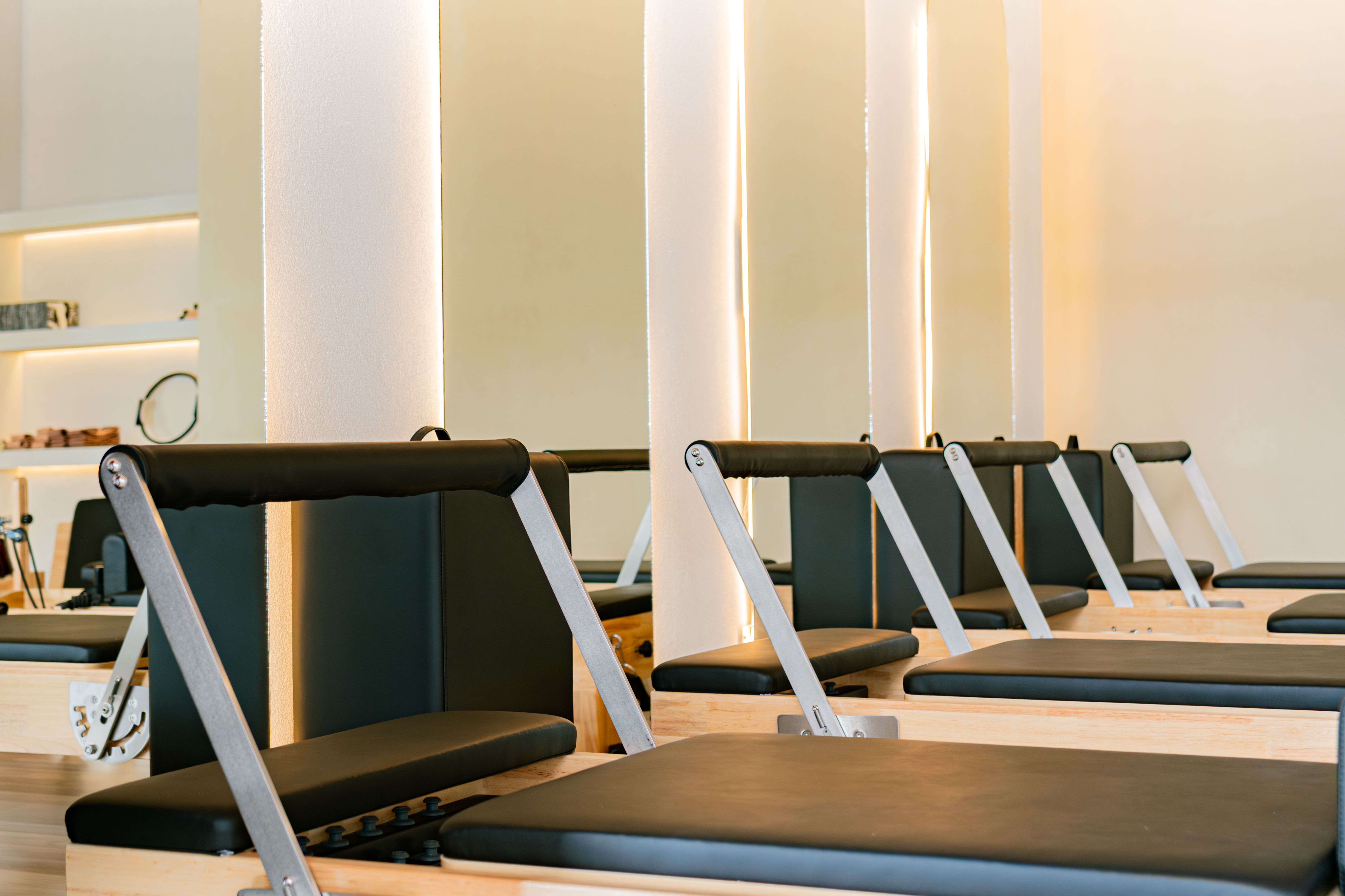 Instructora de pilates guiando a una alumna en un ejercicio de postura en el reformer