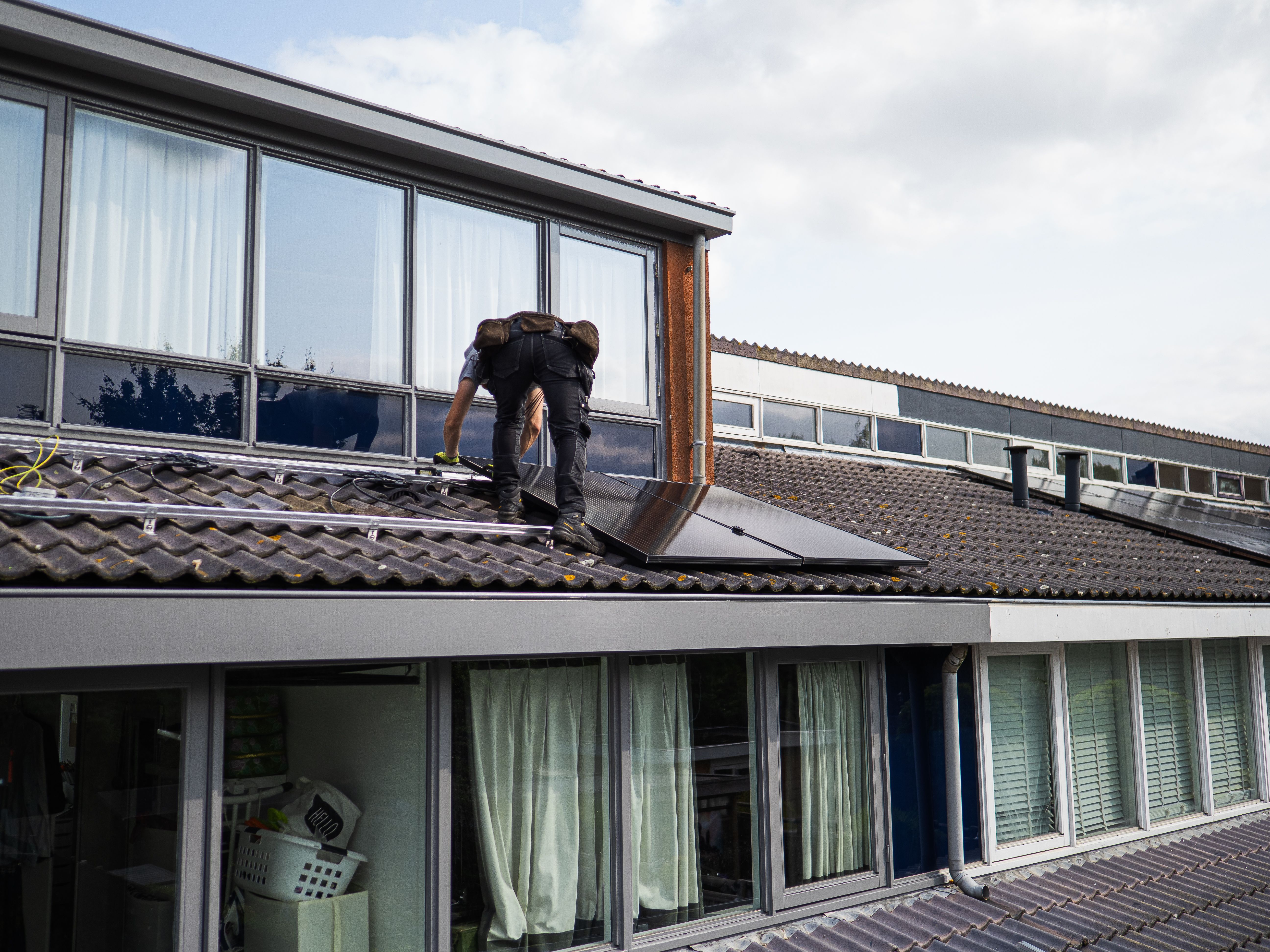Técnico instalando módulos fotovoltaicos en el techo de una vivienda del conurbano bonaerense para autoconsumo